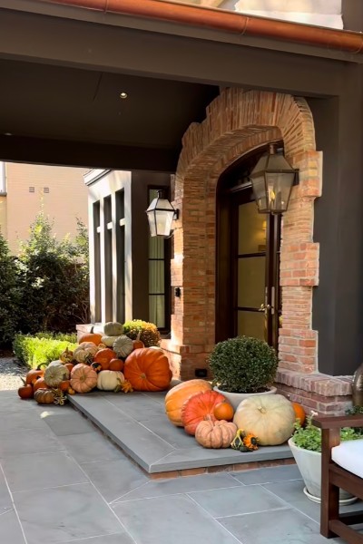 A brick entry dressed with pumpkins, gourds, and autumn mums